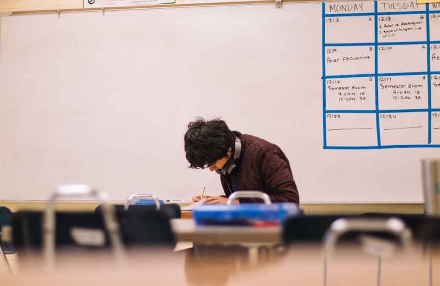 A student preparing for exams in a classroom, exam schedule on the whiteboard behind